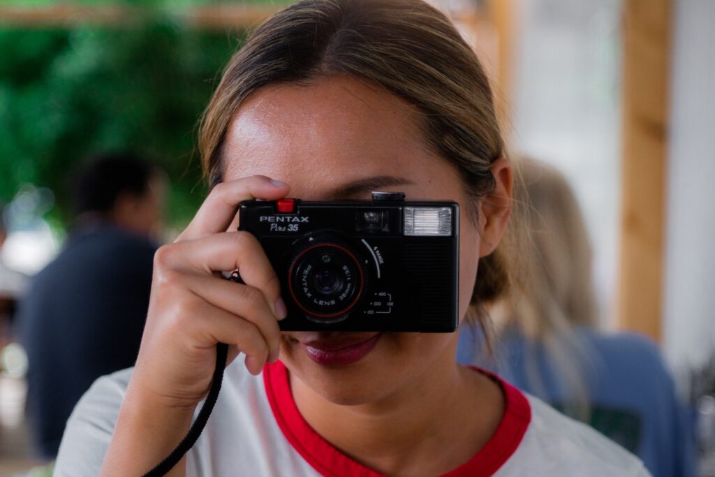 boy in white and red crew neck shirt holding black nikon camera